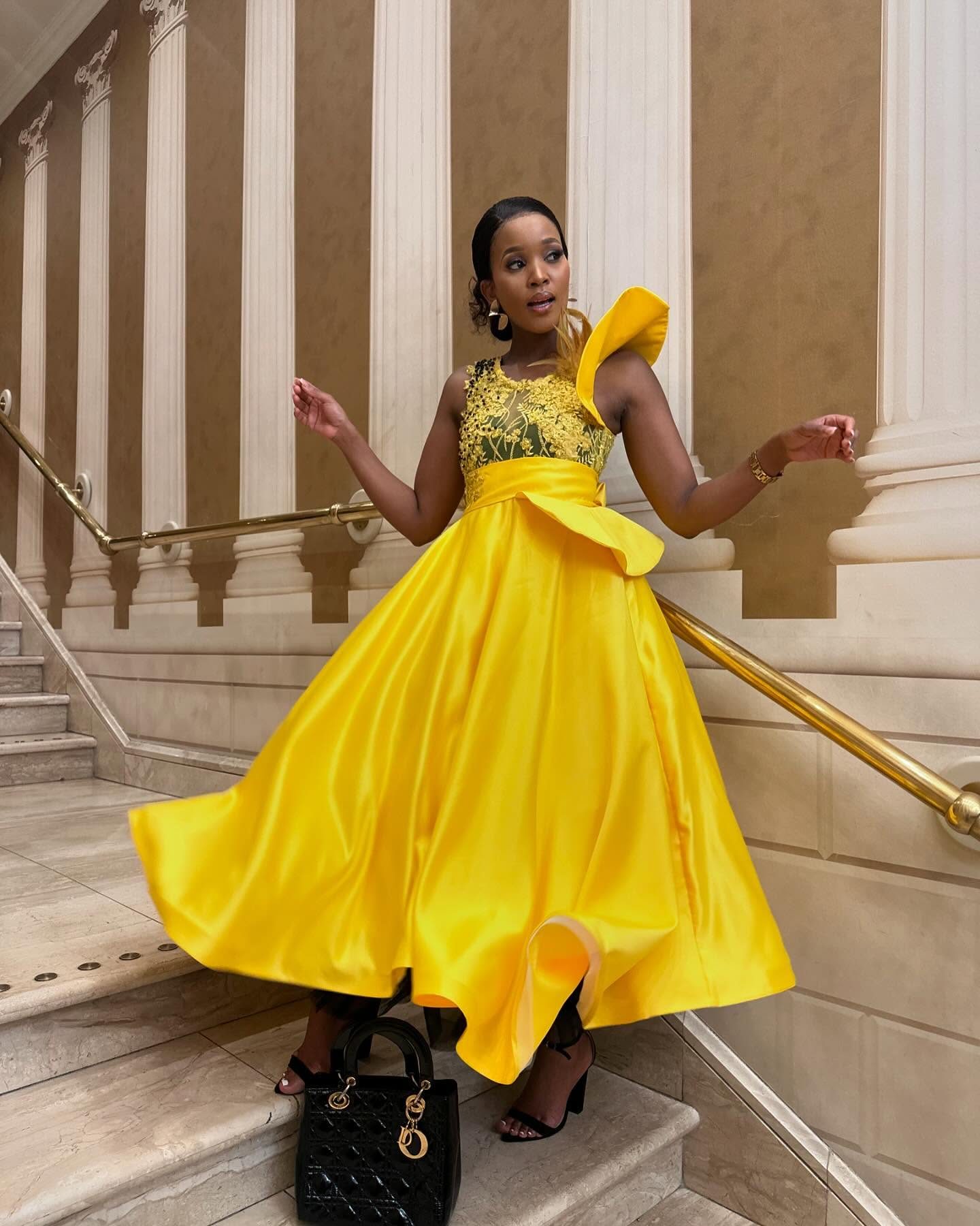 A marigold satin gown with a beaded bodice, worn on a marble staircase.